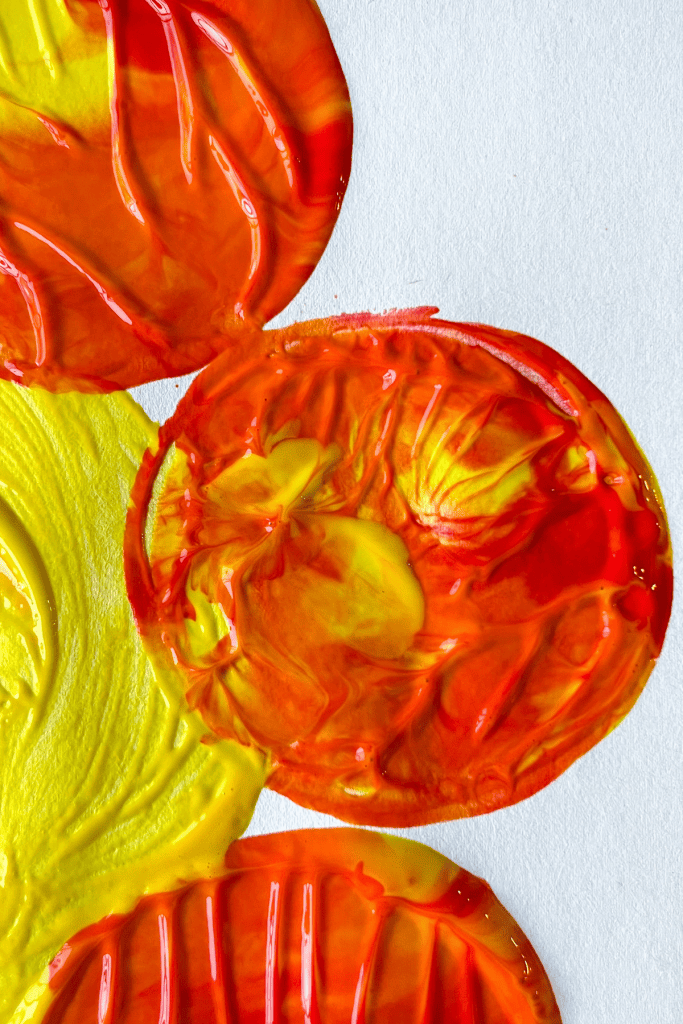 A close up of a yellow, orange, and red flower petal made from dipping the bottom of a plastic cup into yellow, orange, and red paint.
