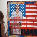 A woman looking at a painting of an American flag inset with a Black woman holding two Black children at her feet. Both the woman and the flag appear to bleed.