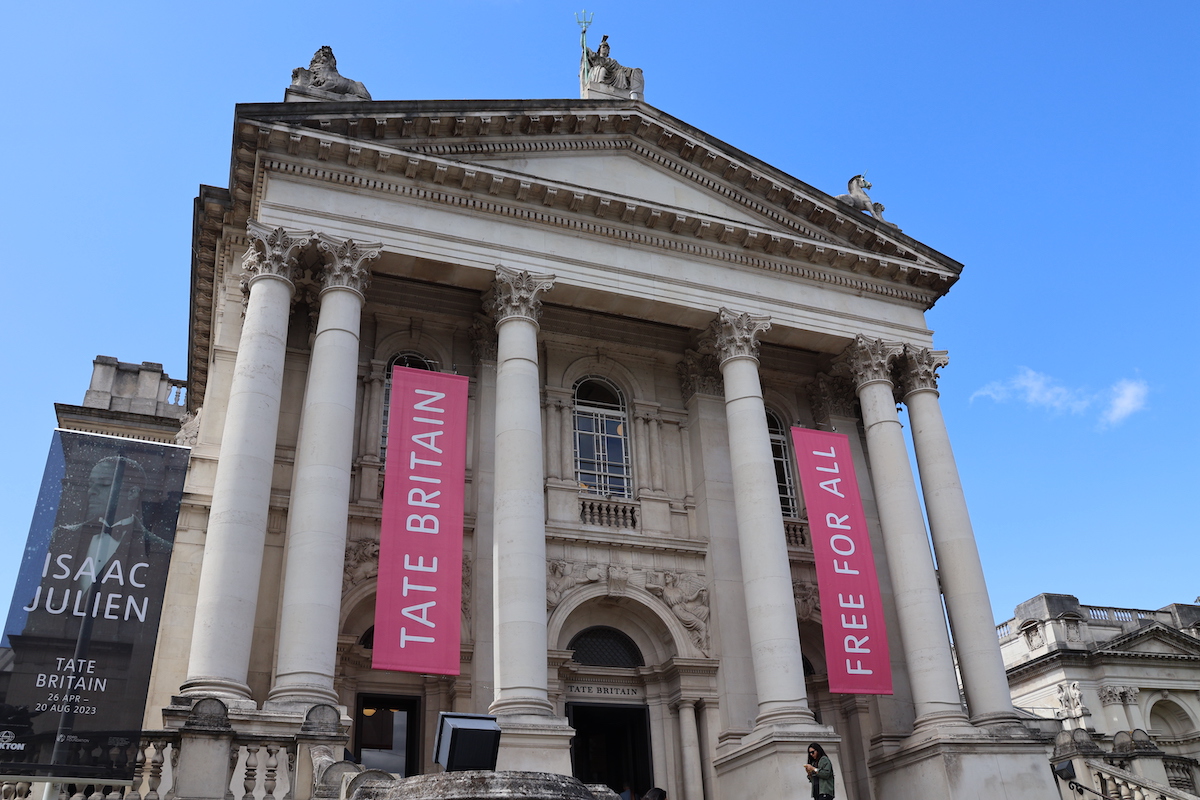 A columnated building facade with pink banners hanging down.
